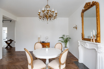 White living room with classic decor, mirror, fireplace, dining table