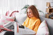 Young woman reading newspaper at home