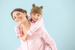 © Pixel-Shot - Portrait of happy mother and daughter in pajamas on color background