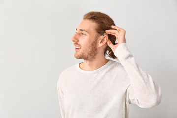 Wall Mural - Young man with hearing aid on white background