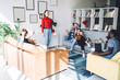 © BullRun - Smiling woman standing in centre of room near joyful friends