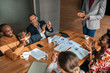 © JonoErasmus - Top view of diverse South African Business team clapping in celebration of a successful boardroom meeting