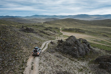 4x4 Suv Car Drive Off-road Path On Dark Rough Terrain, Aerial View. Travel In Steppe Hills Landscape Among Rocks And Stones. Olkhon Island, Siberia, Russia