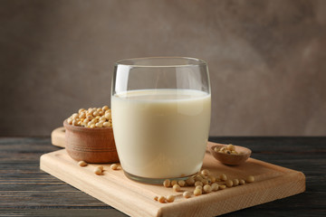 Glass of soy milk and soybeans seeds on wooden background, space for text