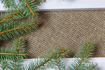 Fir branches and two white painted boards on a background of linen fabric.