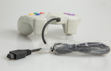 Retro vintage games console controller purple black white red blue green yellow isolated dirty used video game marked scuff wire cable kids playing adults nostalgia old technology shop studio lighting