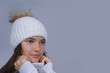 © Bonsales - close-up face portrait beautiful young girl wearing in warm knitted white hat and pullover isolated on gray background with copy space, wintertime trendy fashion concept