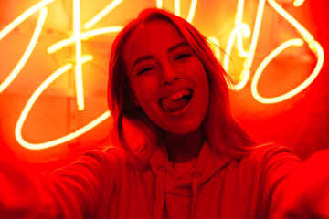 Poster - Image of young caucasian woman standing over red neon text sign outdoors