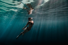 Woman Swimming Underwater In Ocean