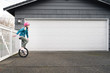 © Cavan Images - Young Girl Riding Unicycle in Driveway on an Overcast Day