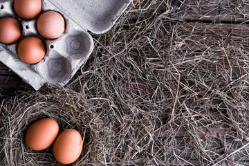 Wall Mural - Chicken eggs in a wicker nest and in a box in a chicken coop top view. Natural organic eggs in the hay. Fresh chicken eggs.