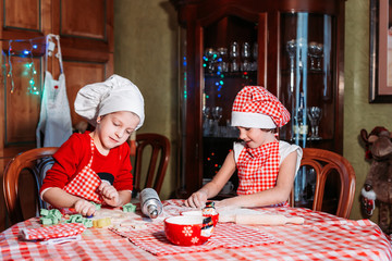 Cute, little girls in chef uniform with apron and hat making ginger cookies