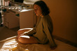 © Dmytro Bilous/Stocksy - beautiful girl sitting in a sweater on the bed with backlight soft