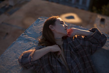 Portrait Of A Girl With Long Hair In A Coat On The Edge Of The Roof In The Rays Of Sunset
