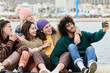 © guille Faingold/Stocksy - Young friends taking selfie on pier