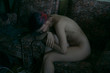 © Dmytro Bilous/Stocksy - Woman without clothes sitting in a chair sad