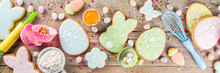 Easter Cooking Baking Background With Pastel Colored Easter Cookies, Sugar Sprinkles And Ingredients For Bake Cake And Cookies.  Wooden Rustic Background, Flatlay Banner Copy Space