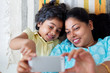 © SAPTAK GANGULY/Stocksy - Mother and daughter taking selfie with mobile phone lying on a rug