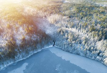 Wall Mural - Beautiful aerial view from drone of winter landscape with forest, snow, frozen lake and river. Rime ice and hoar frost covering trees.