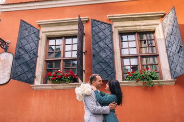 couple in love on orange building background. girl holding a bou