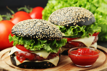 Two black burgers with vegetables and beef meat	