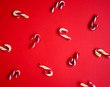 Christmas texture. Candy canes on red background, geometric order, top view.