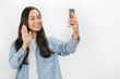 © InsideCreativeHouse - Portrait of adorable brunette asian woman using cellphone showing Hi gesture while making video call over white background