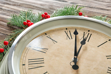 Clock and fir branches on wooden background, closeup. Christmas countdown concept