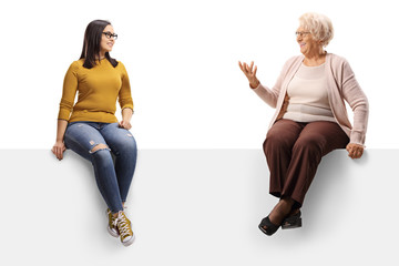 Poster - Young and senior woman sitting on a panel and having a conversation