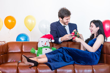 Young man giving gift to his girlfriend for  Christmas and New Year's Eve celebrations.