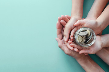  child and adult holding money jar, donation, saving, charity, family finance plan,  superannuation, household budget, inflation financial crisis concept