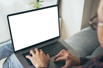 mockup image blank screen computer with blank white background for advertising text,hand man using laptop contact business search information on desk at home office.marketing and creative design