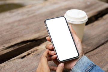 Mockup image blank white screen cell phone.men hand holding texting using mobile on desk at home office. background empty space for advertise text.people contact marketing business and technology 