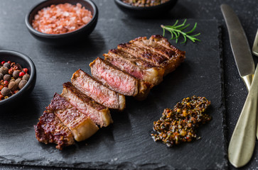 Poster - New york strip loin beef steak meat with chimichurri sauce against black stone background