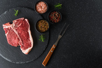 Poster - Raw t-bone porterhouse beef steak meat with chimichurri sauce against black stone background