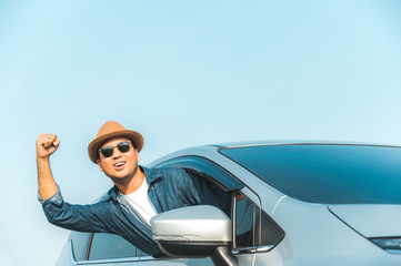 Young handsome asian man driving car to travel on his holiday vacation time with beautiful blue sky.