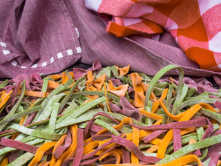 Wall Mural - Homemade pasta, farfalle bow-tie, fettuccine or tagliatelle colorful pasta on grey background with flour, Colorful butterfly pasta. Italy ingredients for lunch.