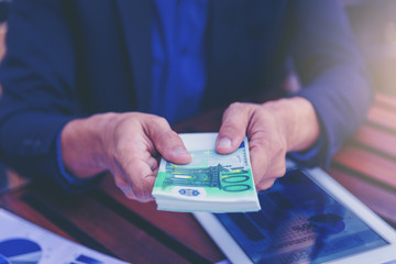 Wall Mural - Businessman giving EURO money to you for business achieved on the table