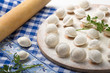 © Maria - Pelmeni, little dumplings lie on a cutting board, sprinkled with gray flour, top view.