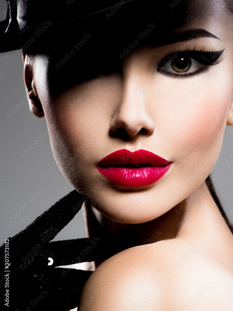 Сlose-up portrait of a woman in a black hat and gloves with red lips - obrazy, fototapety, plakaty 