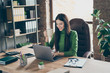 © deagreez - Profile photo of pretty young business lady looking screen notebook table modern user chatting partners drink hot tea mug sitting boss chair wear green turtleneck modern interior office