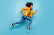 Full length profile photo of beautiful dark skin lady jumping high running sale shopping rushing wear overcoat jeans green sweater scarf isolated blue color background