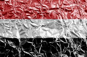 Wall Mural - Yemen flag depicted in paint colors on shiny crumpled aluminium foil closeup. Textured banner on rough background