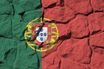 Portugal flag depicted in paint colors on old stone wall closeup. Textured banner on rock wall background