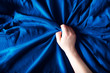Woman hand on blue silk bedding, sex and orgasm concept