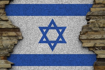Israel flag depicted in paint colors on old stone wall closeup. Textured banner on rock wall background