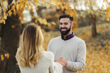 Wall Mural - Playful couple having fun while holding hands during autumn day.