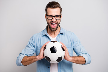 Poster - Photo of attractive handsome guy holding leather white black soccer ball yelling loud supporting team football match wear specs casual denim outfit isolated grey color background