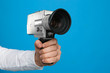 © New Africa - Man with vintage video camera on light blue background, closeup of hand