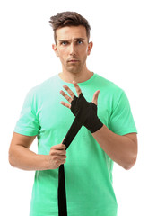 Sticker - Sporty young man applying wrist bands against white background